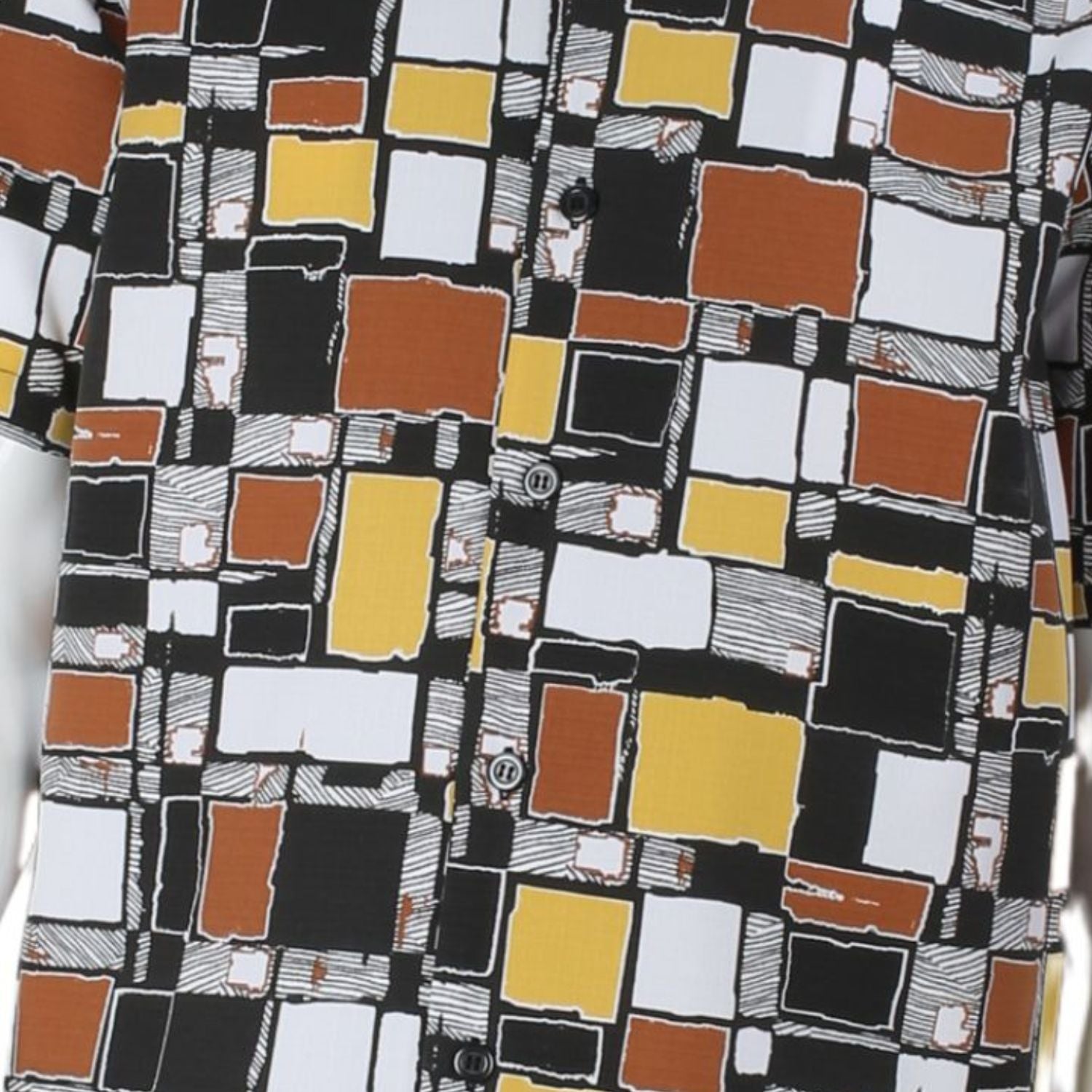 Close up of mosaic square pattern shirt in black, mustard, orange, and white