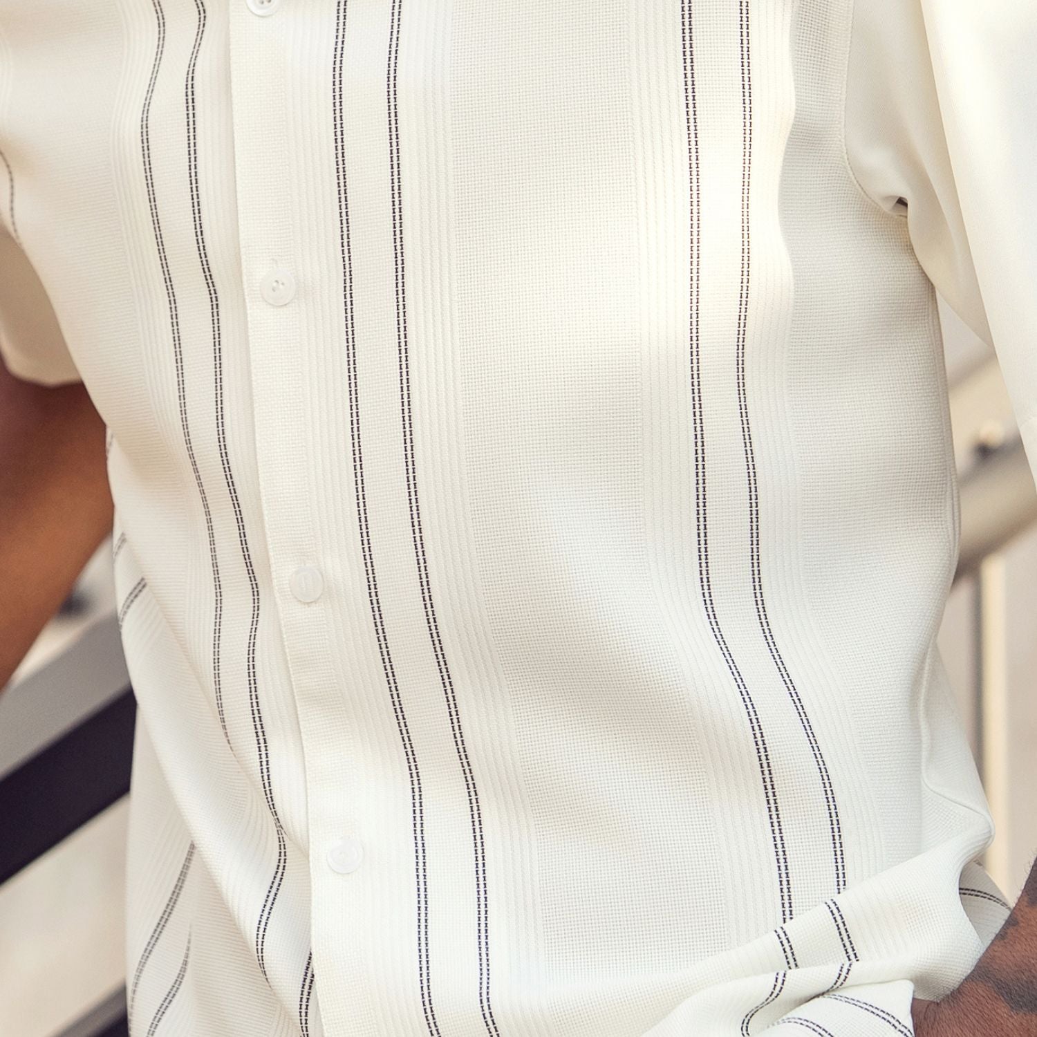 Close-up of cream walking suit shirt showing the detailed textured micro-grid and vertical line paneling.