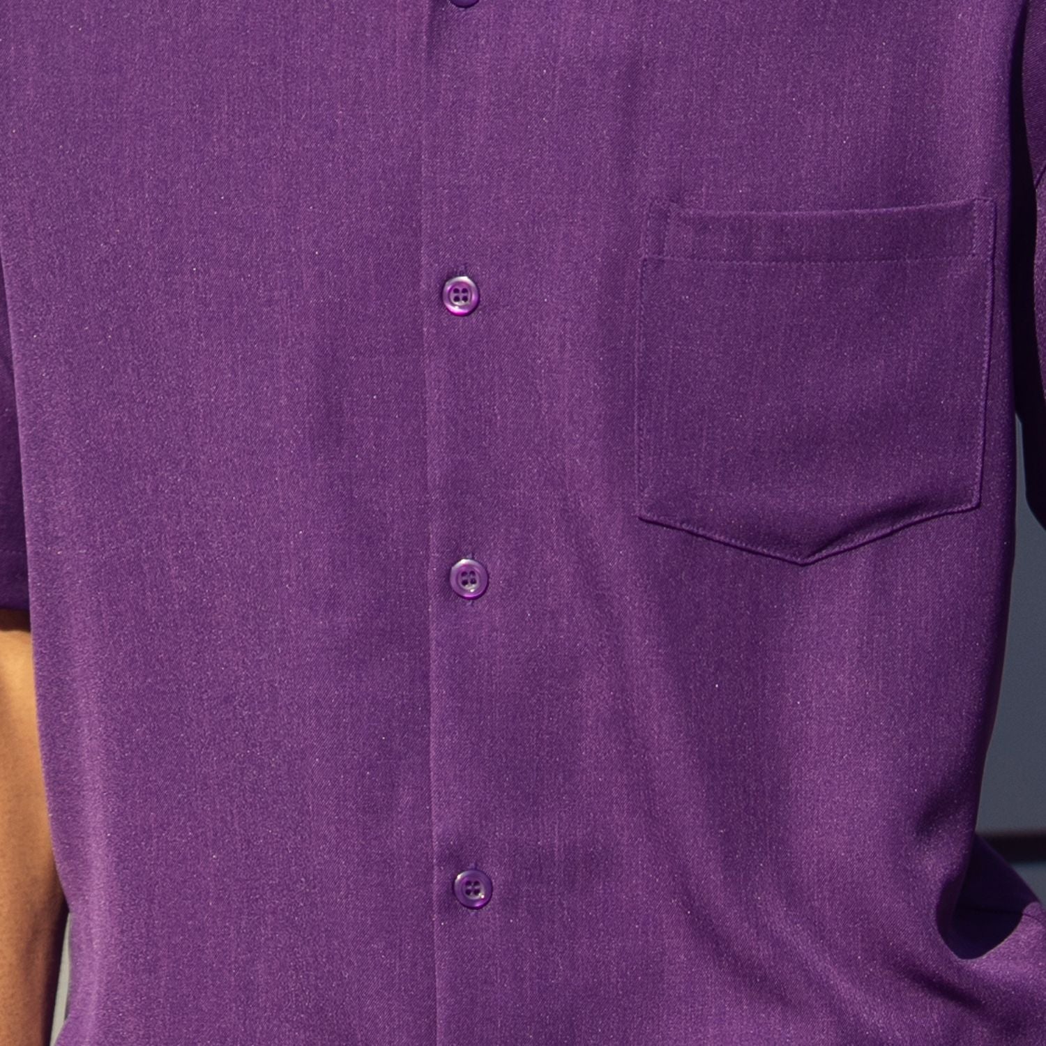 Close-up of purple 100% polyester fabric showing the solid texture and button detail