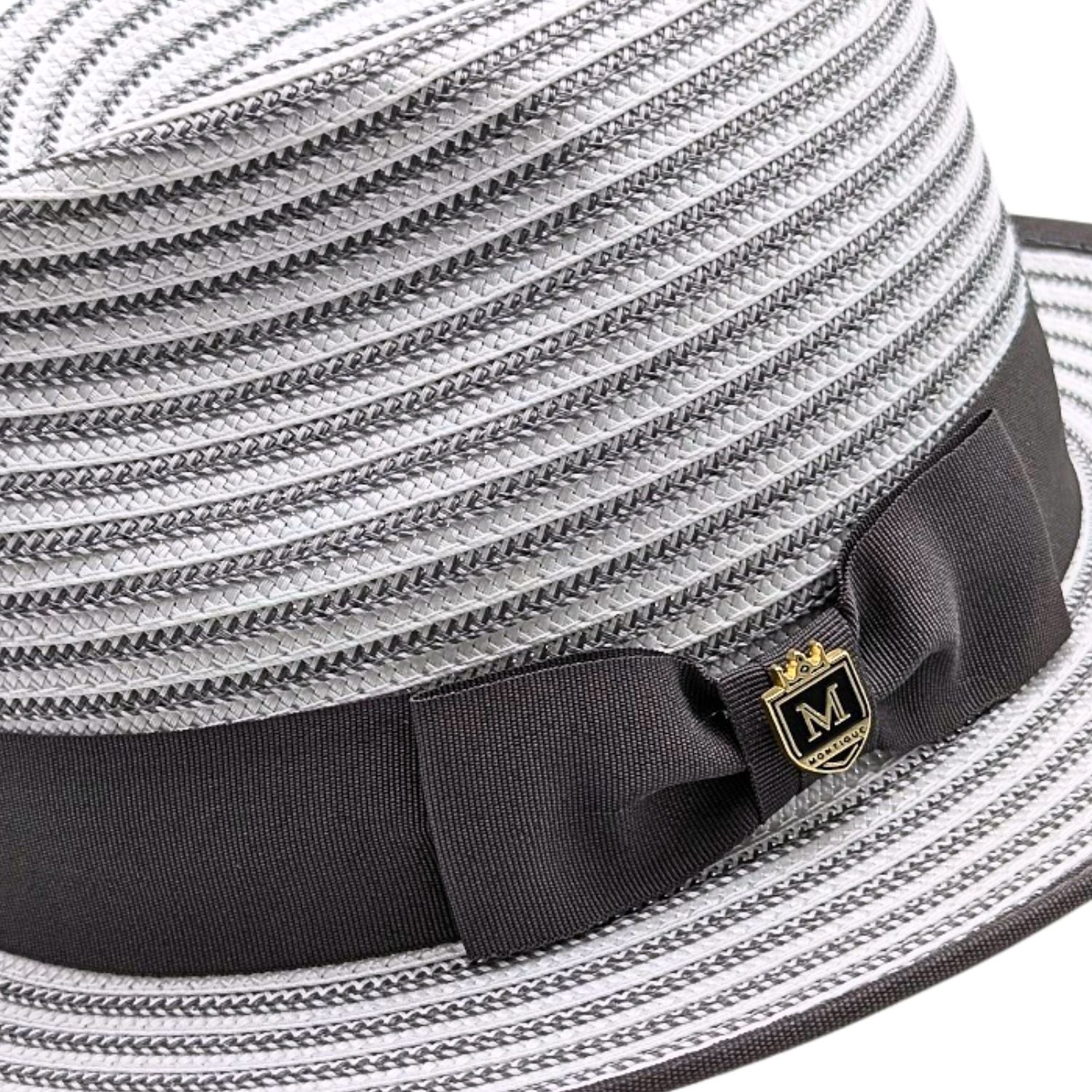 Grey Montique fedora close-up showing woven striped crown, dark grey grosgrain bow, logo pin, and matching brim trim