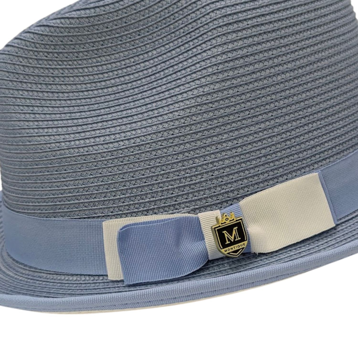 close up of Montique Carolina straw fedora hat with bow, ribbon band, and logo pin