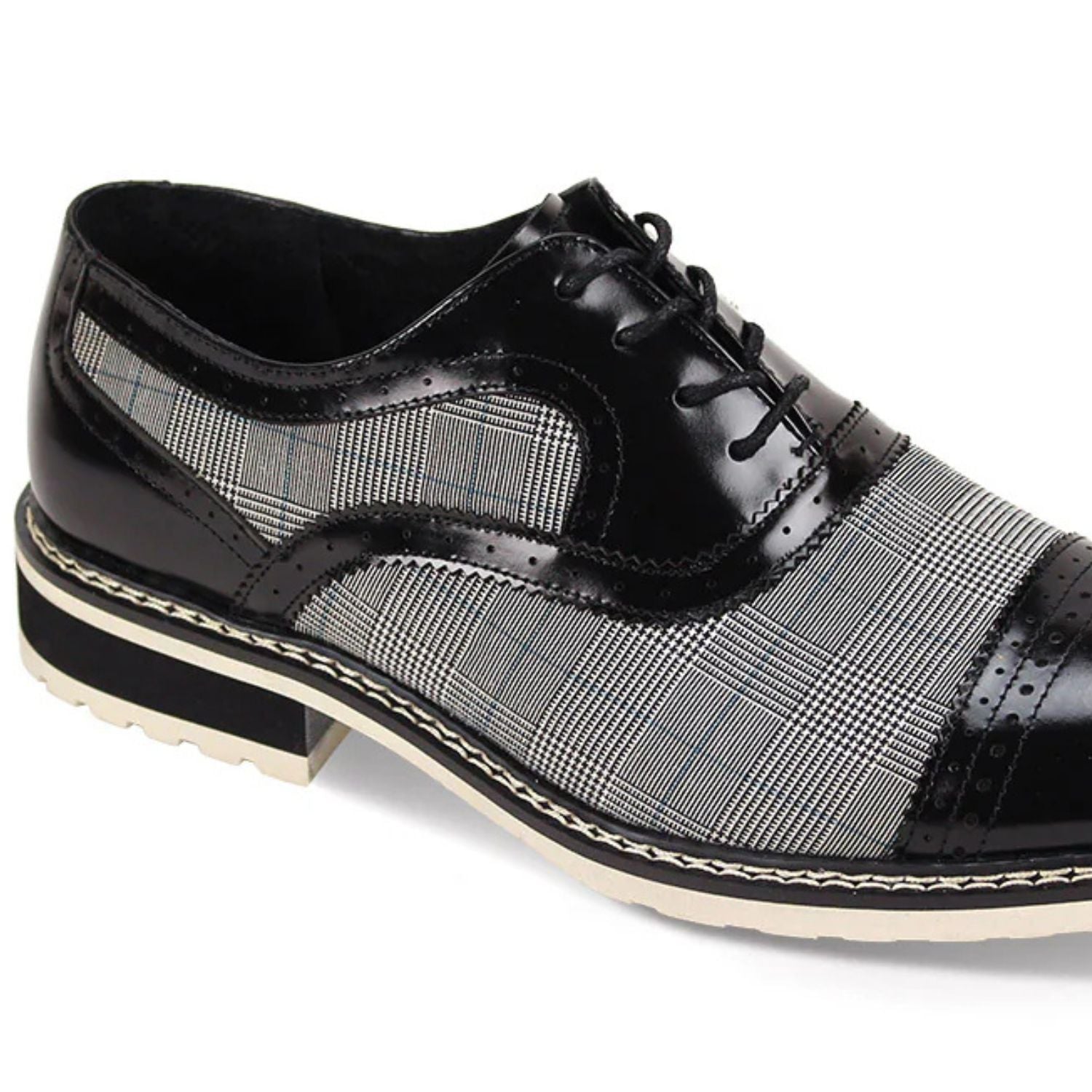 Close-up detail of black leather brogue stitching and grey checkered tweed texture.