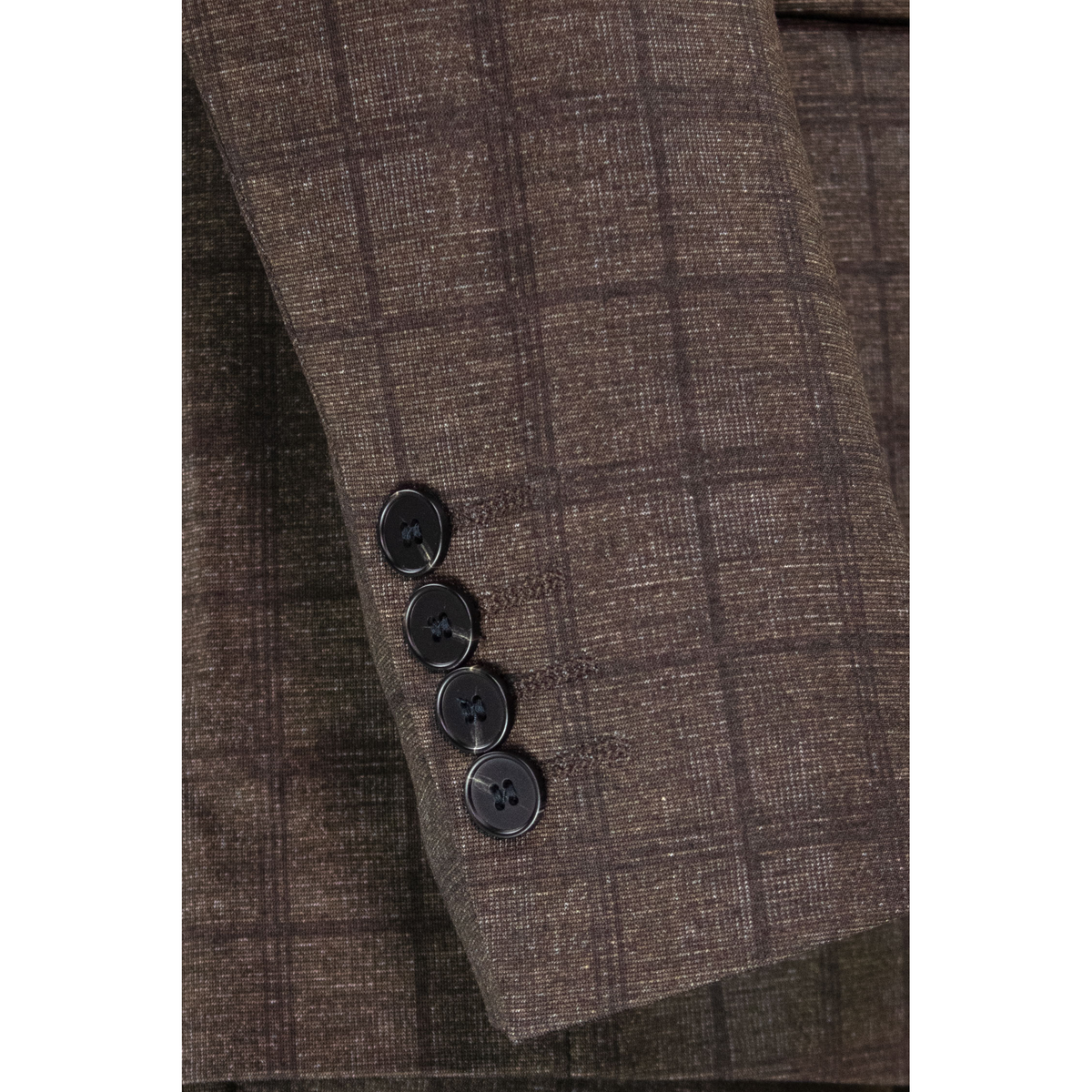 Close-up of the brown Glen plaid jacket sleeve, showing four dark cuff buttons and the woven check pattern.