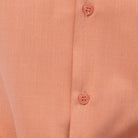 Close-up of peach 100% polyester fabric showing the solid texture and button detail