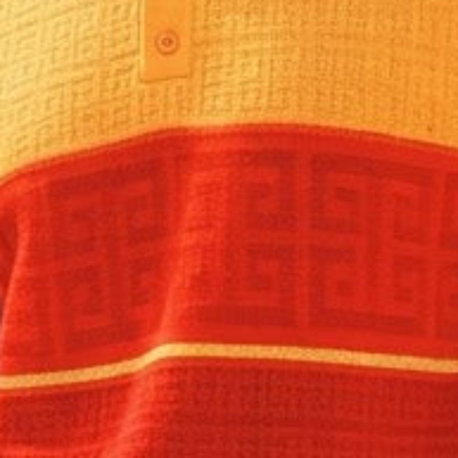 close-up of gold knit polo shirt with greek key border pattern