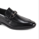 Close-up three-quarter view of men’s black moc-toe loafer with metallic bit hardware