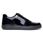 Side profile of black velvet and patent leather court sneaker