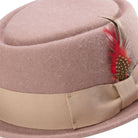 close up side view tan pork pie hat with feather and ribbon band