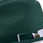 Emerald green straw hat with a green white ribbon and gold emblem on a white background
