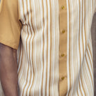 Close-up of mustard and white woven vertical stripe panel detail on a men's short sleeve walking suit shirt.