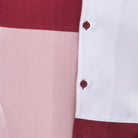 Close-up of ruby and blush walking suit shirt showing the clean color block panels and coordinated tonal buttons.