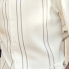 Close-up of cream shirt fabric showing the detailed micro-grid texture and vertical contrast lines.