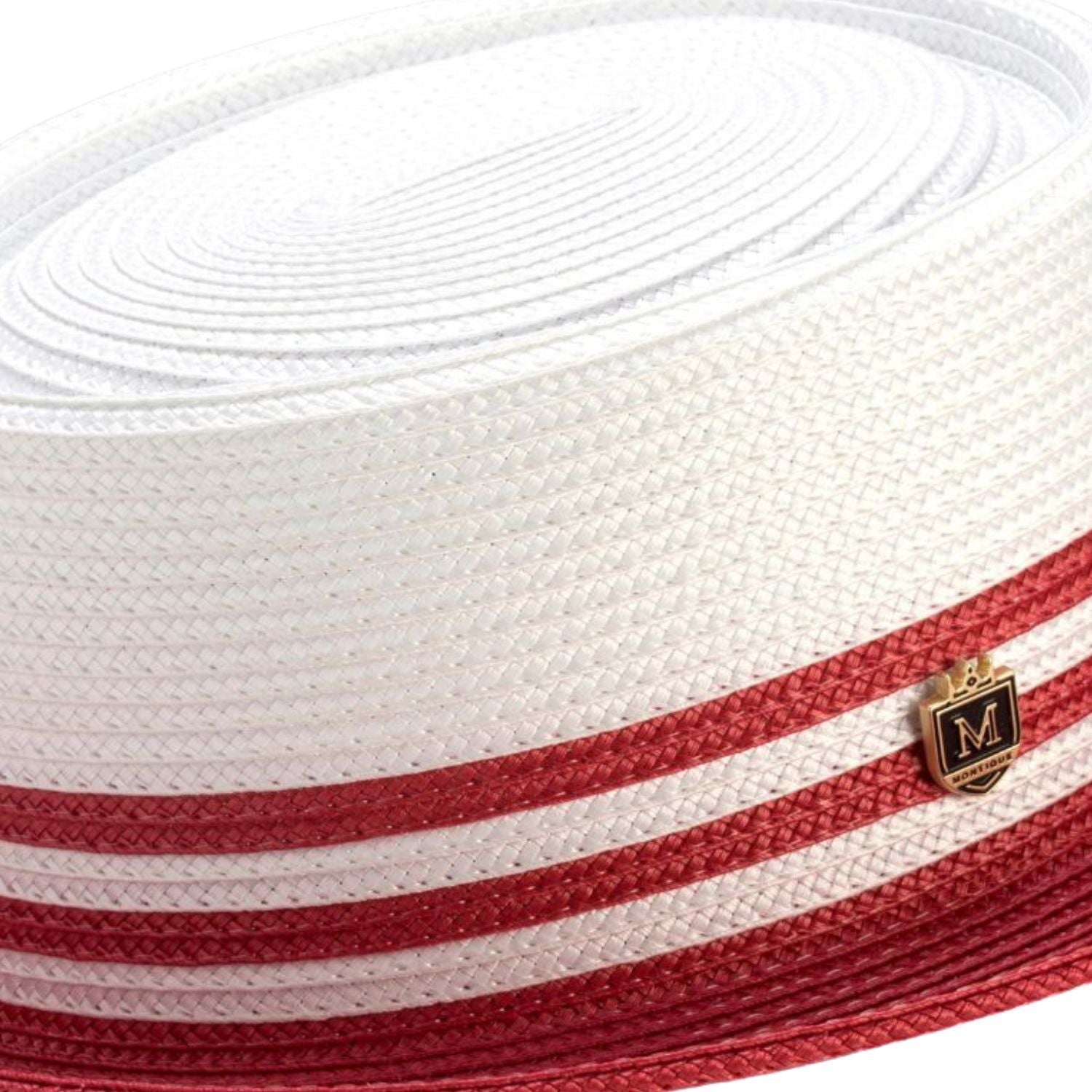 Close-up of the red striped ribbon and signature Montique metal pin on a white straw pork pie hat.