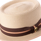 Side view of beige pork pie hat with brown grosgrain ribbon and pink stripe
