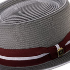 Side view of grey pork pie hat with burgundy grosgrain ribbon and pink stripe