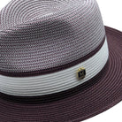 Wine and white Montique fedora hat close-up with woven crown, white band, wine brim, and logo pin