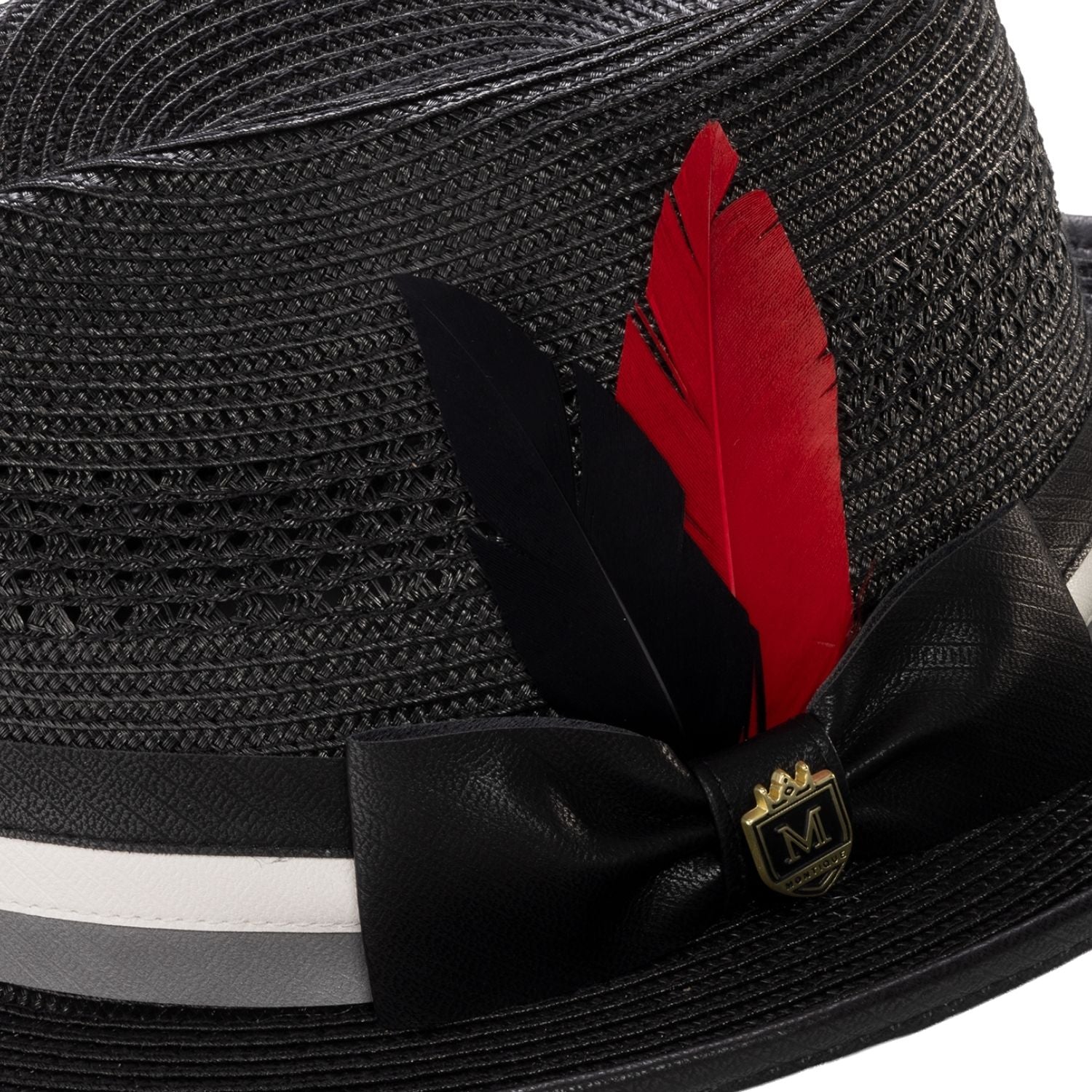 Close-up of black mesh fedora showing the striped satin ribbon, signature red feather, and Montique metal crest pin.