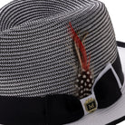 Side view of black and white Montique fedora hat with ribbon and feather