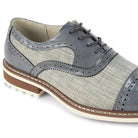 Close-up of grey leather brogue stitching and textured salt-and-pepper tweed fabric.