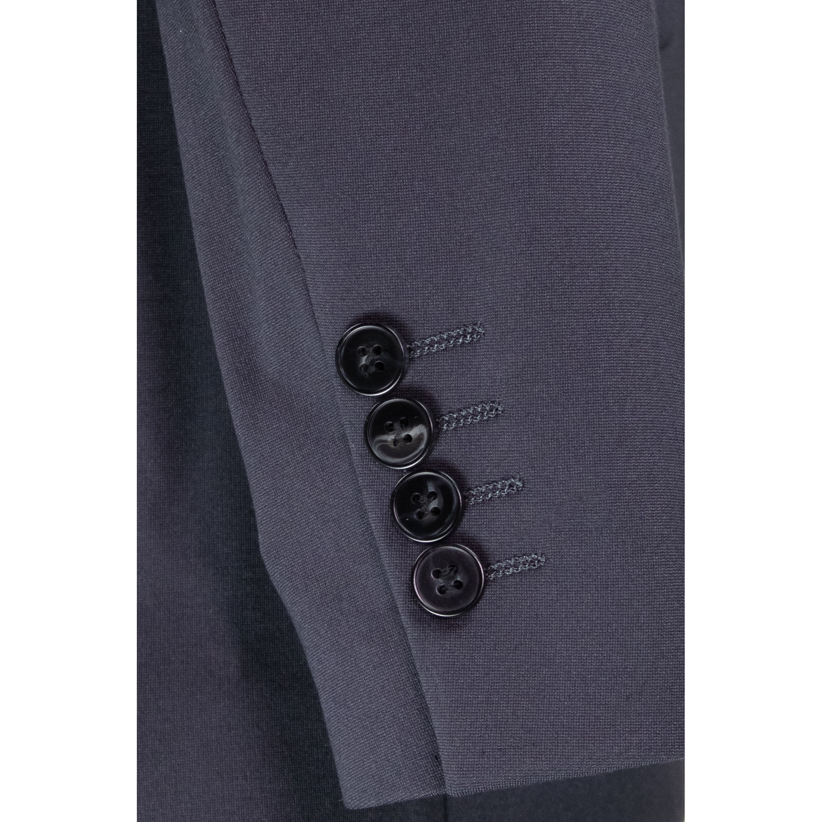 Close-up of the charcoal jacket sleeve, showing four dark cuff buttons and fine fabric texture.