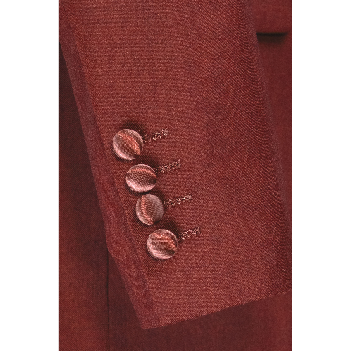 Close-up of the burgundy jacket sleeve, showing four satin-covered cuff buttons and textured fabric.